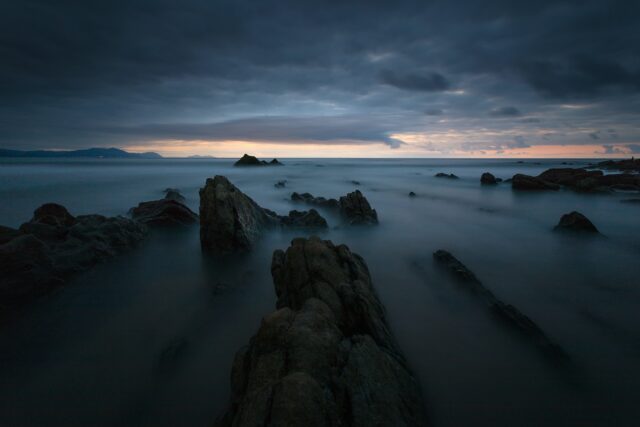 rock formations on body of water under cloudy sky