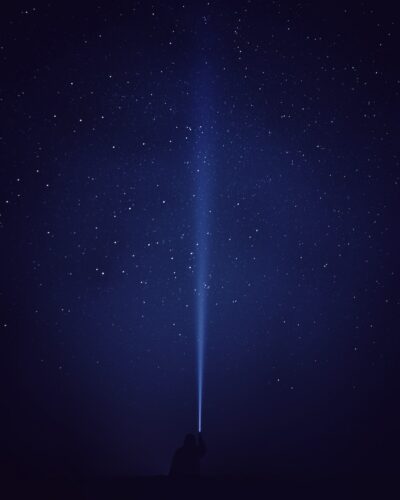 silhouette of person with flash light under starry night