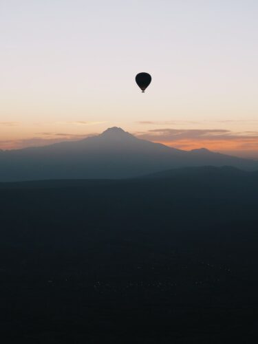 a hot air balloon flying over a mountain range