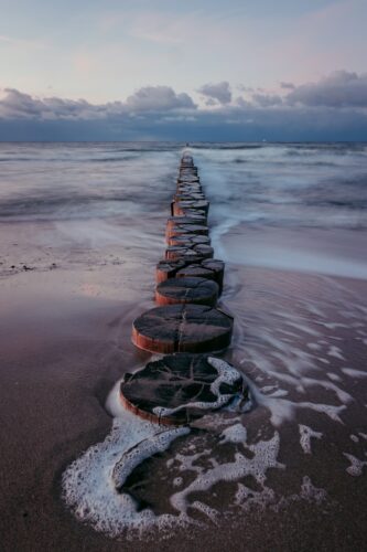 A long row of rocks sitting on top of a sandy beach