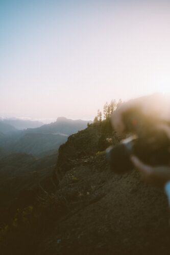 a person standing on top of a mountain holding a cell phone