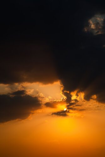 a plane flying in the sky at sunset