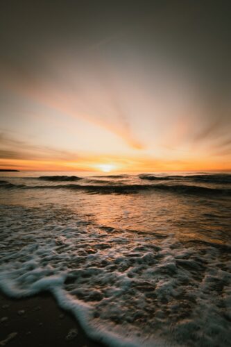 The sun is setting over the water at the beach
