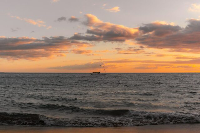 A boat is out in the ocean at sunset