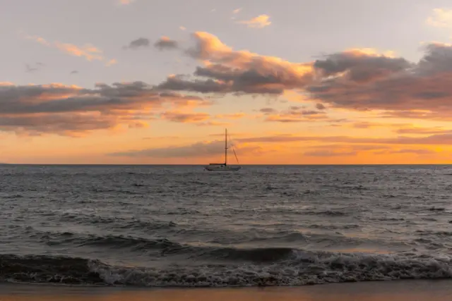 A boat is out in the ocean at sunset