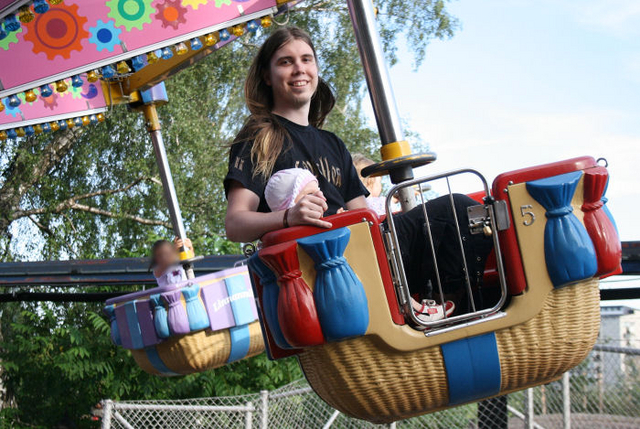 Rolle-isä Lotan kanssa pallokarusellissa. Lottaa ei paljon kuvassa näy koska hän on niin lyhyt. Rolle hymyilee leveästi ja tukka hulmuaa.